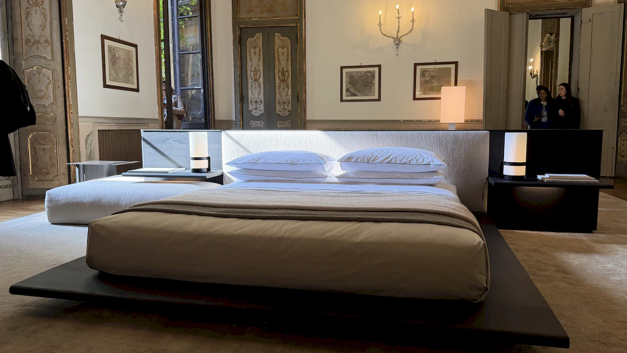 A minimalist bedroom featuring a low platform bed, set within a classic, palatial residence in Milan.