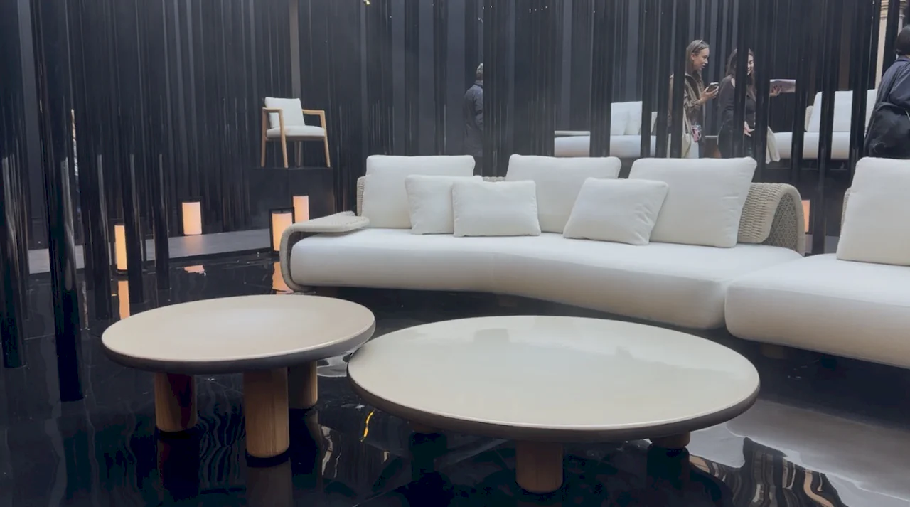 A contemporary living room set featuring a white curved sofa and circular side tables on a glossy laminate floor.