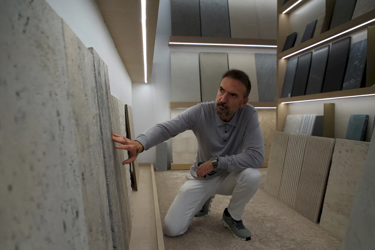 Architect Manuel Ruiz Moriche examining textures and natural stone materials at a design exhibition.