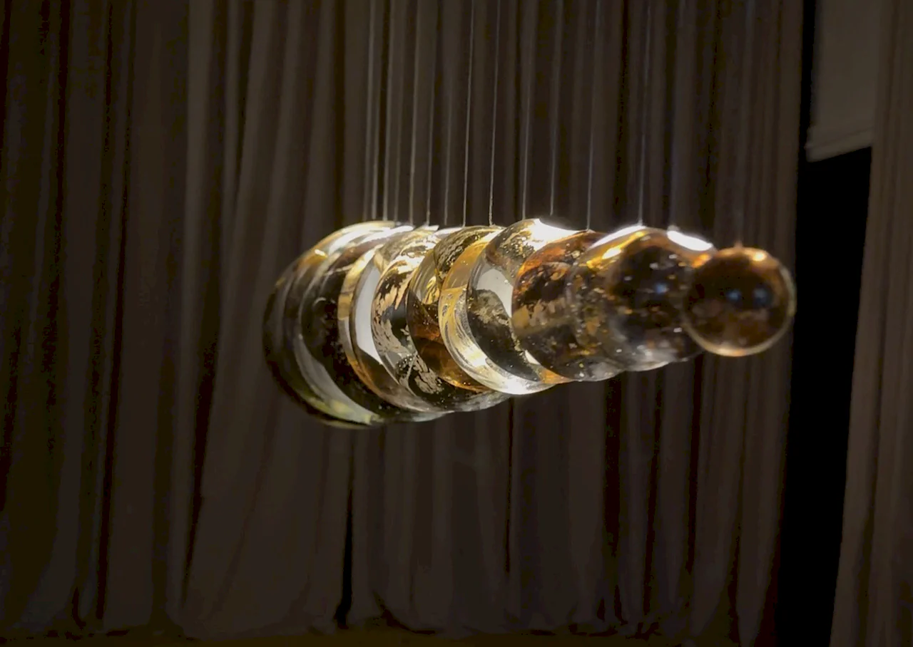 Artistic suspended lighting sculpture featuring glass spheres and metallic finishes at the Milan Fair.