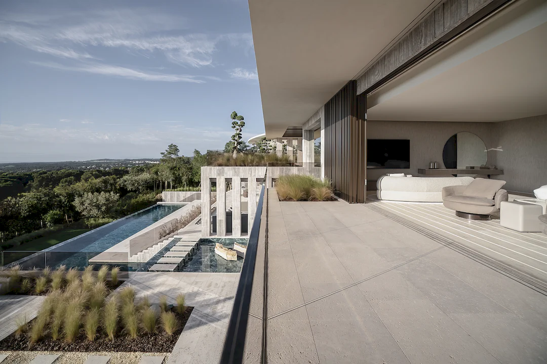 A panoramic view from the open-plan living room of Villa ENSO, showcasing the natural stone terraces, the ponds and the design by Manuel Ruiz Moriche.