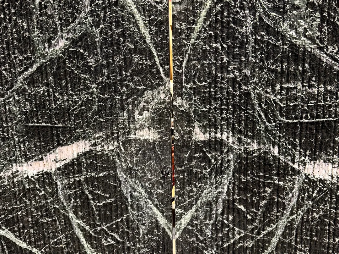 A close-up of the texture of dark natural stone with light veins, selected by Manuel Ruiz Moriche of ARK Architects during his visit to Marmomac.